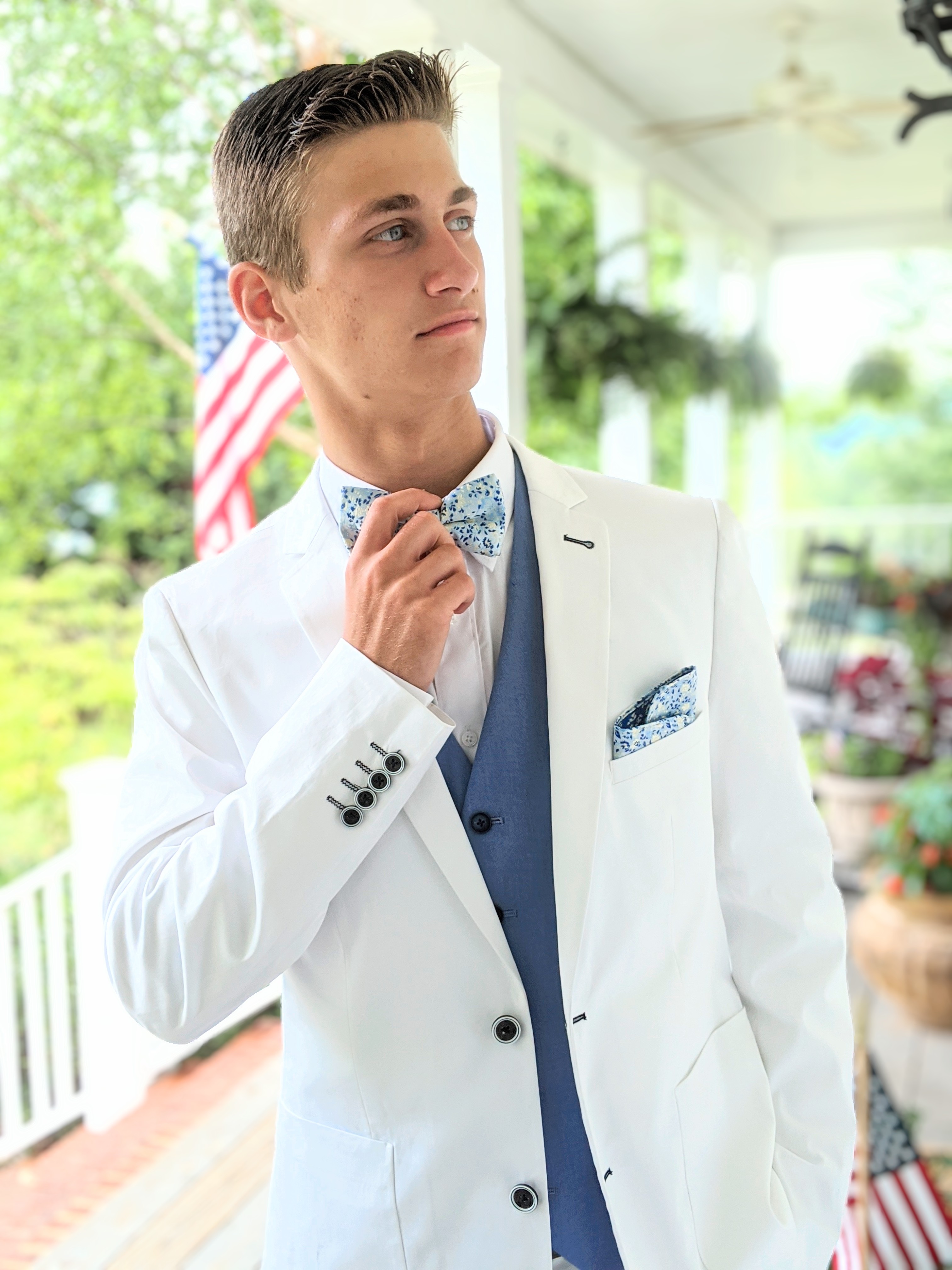 Handsome man in white suit with blue vest and blue floral bowtie