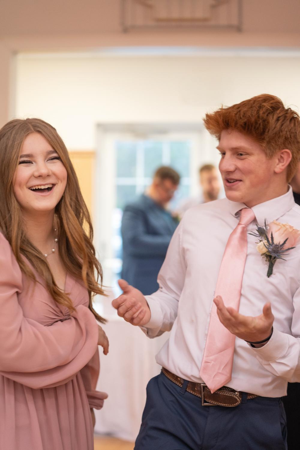 Groomsmen with red hair smirks at bridesmaid sister in pink dress